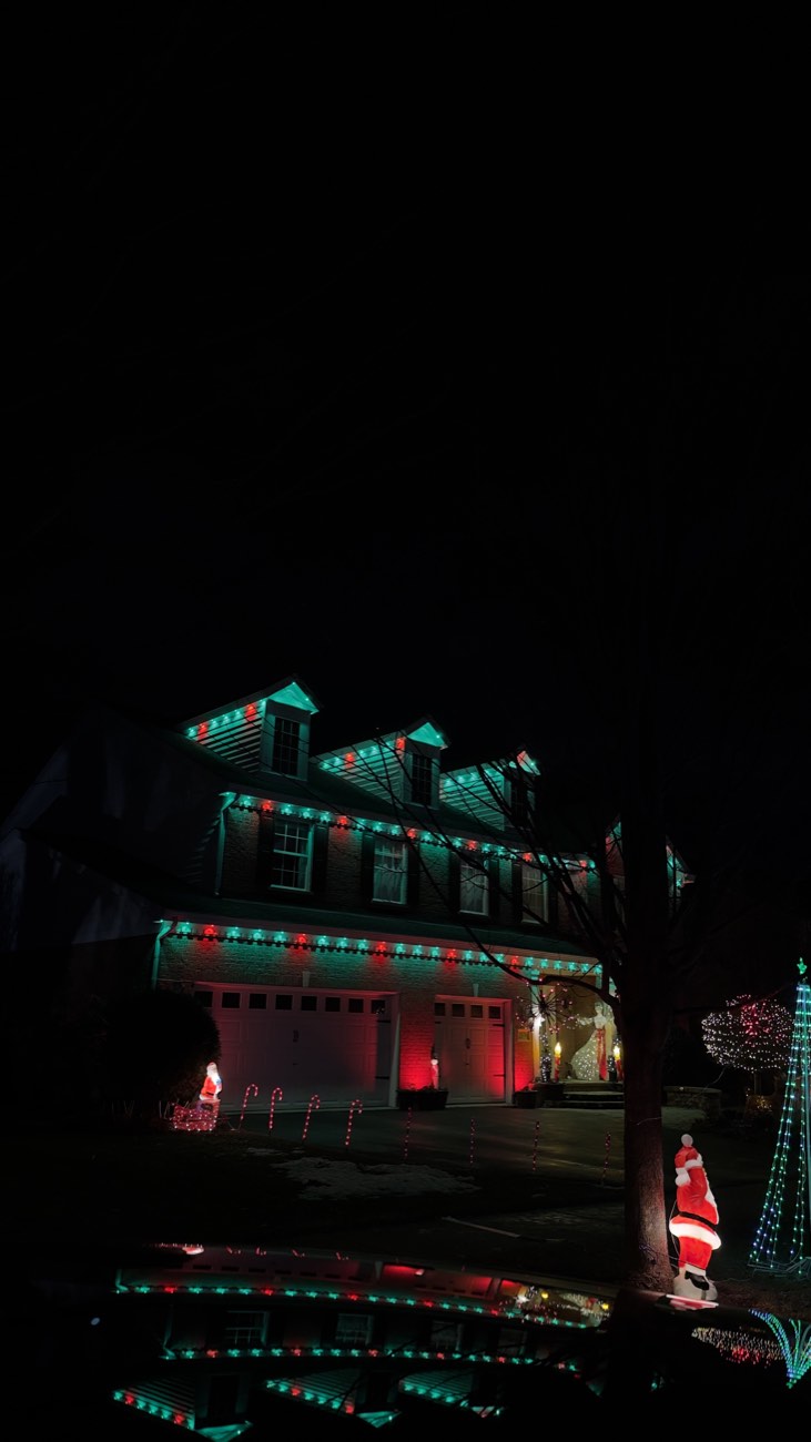 Red and green Christmas roofline lights with holiday yard displays