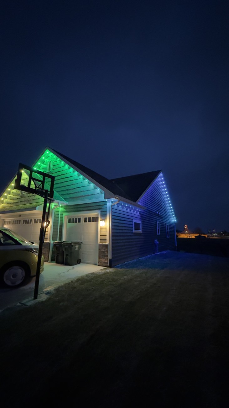 Permanent color-changing roofline lighting installed on a home at night